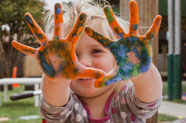 Child proudly showing off hands with finger paint