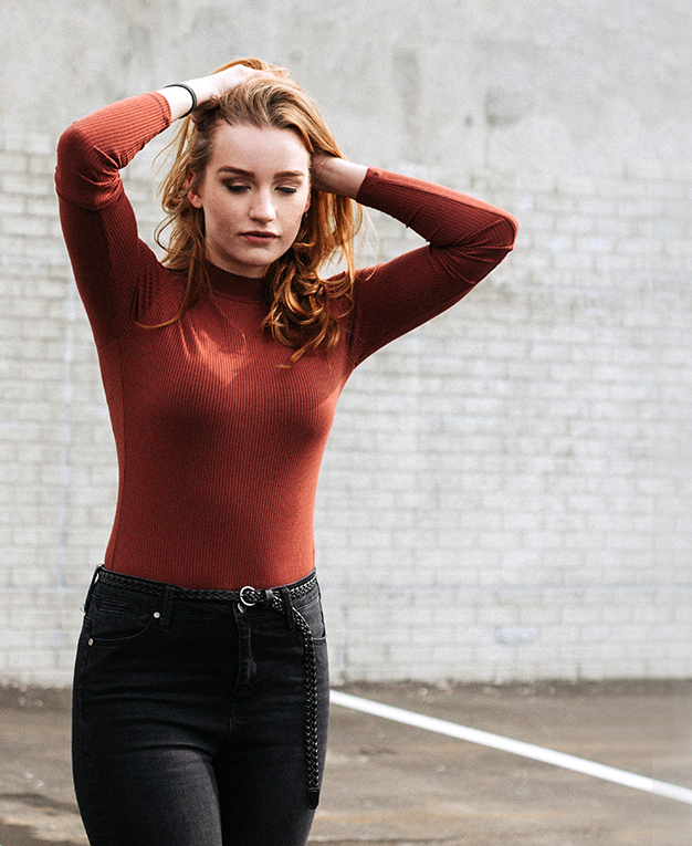BodyTite woman in tight sweater brushing back hair
