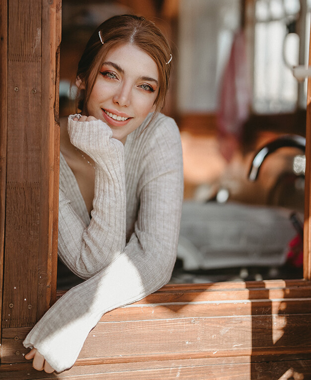 Injectables & dermal fillers young woman in sweater leaning on kitchen window